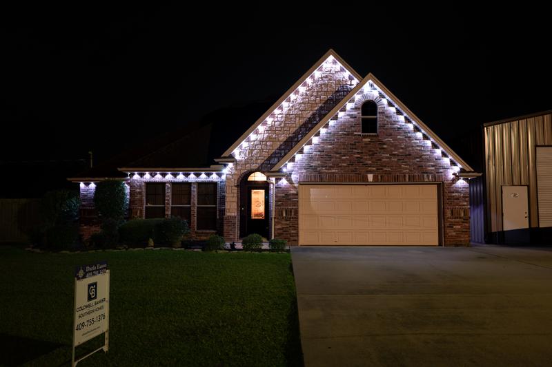 Front exterior with white permanent holiday lights at night